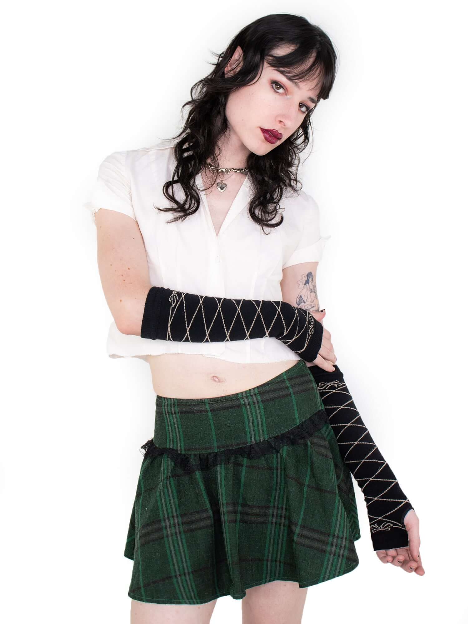 Further away photo of model wearing gloves, styled with white blouse and green plaid skirt