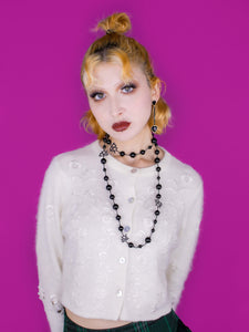Mid shot of necklace, model looking into camera, also wearing black crush earrings