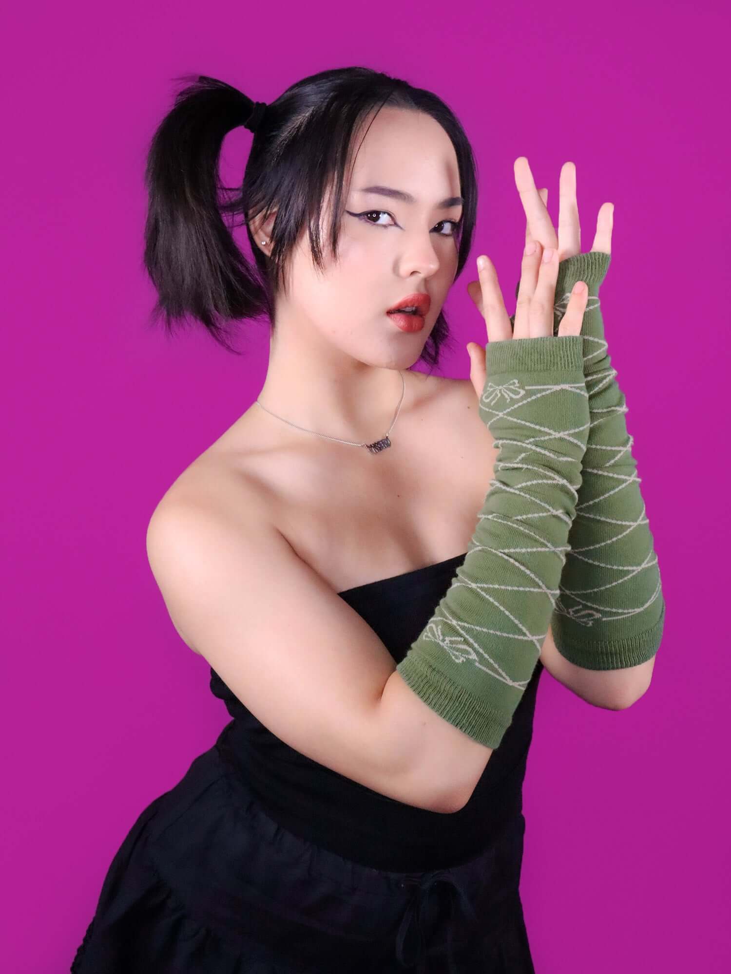 Model holding up arms showing the green and cream color of the arm warmers